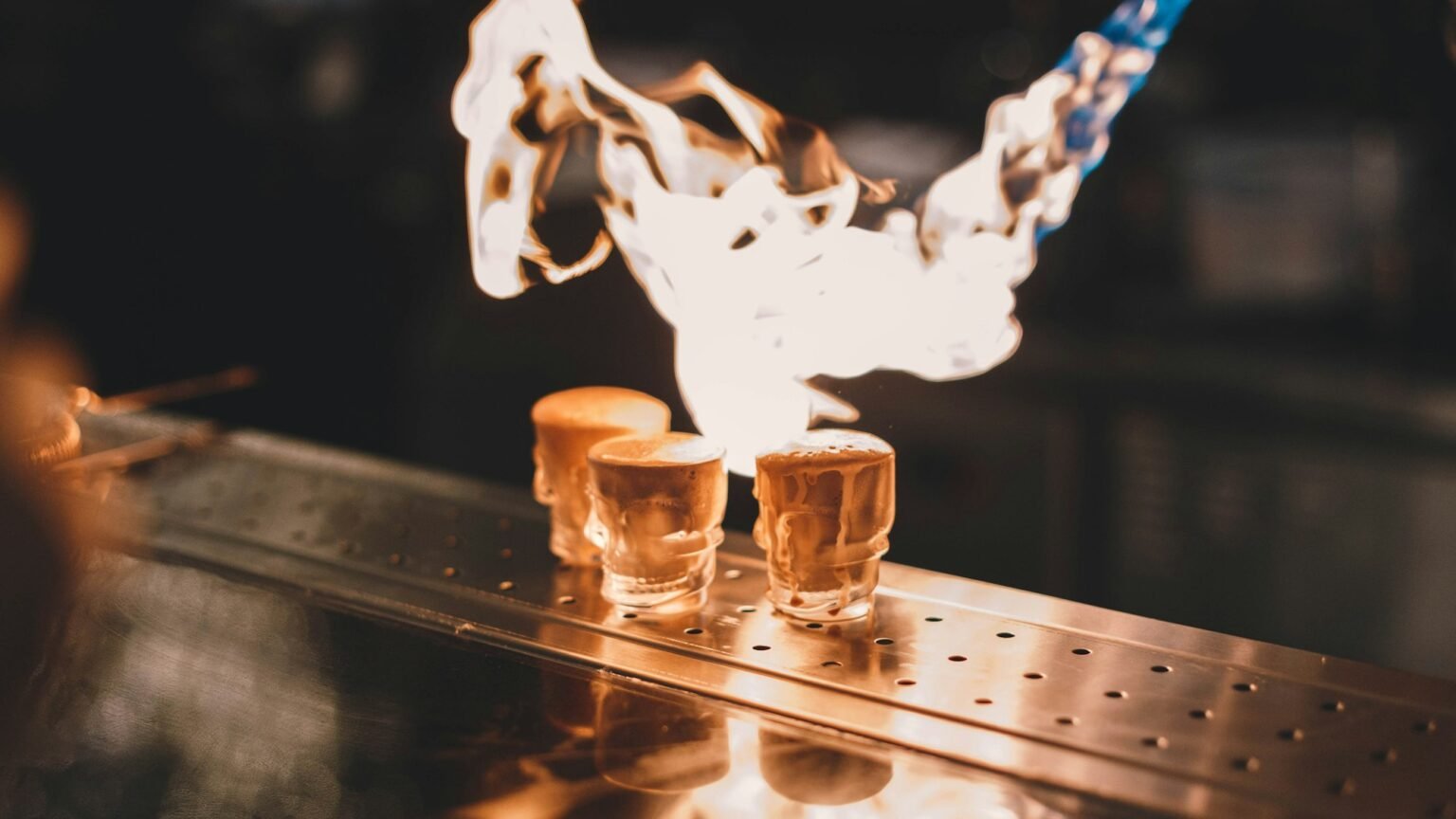 A burst of flame over cocktail glasses on a bar