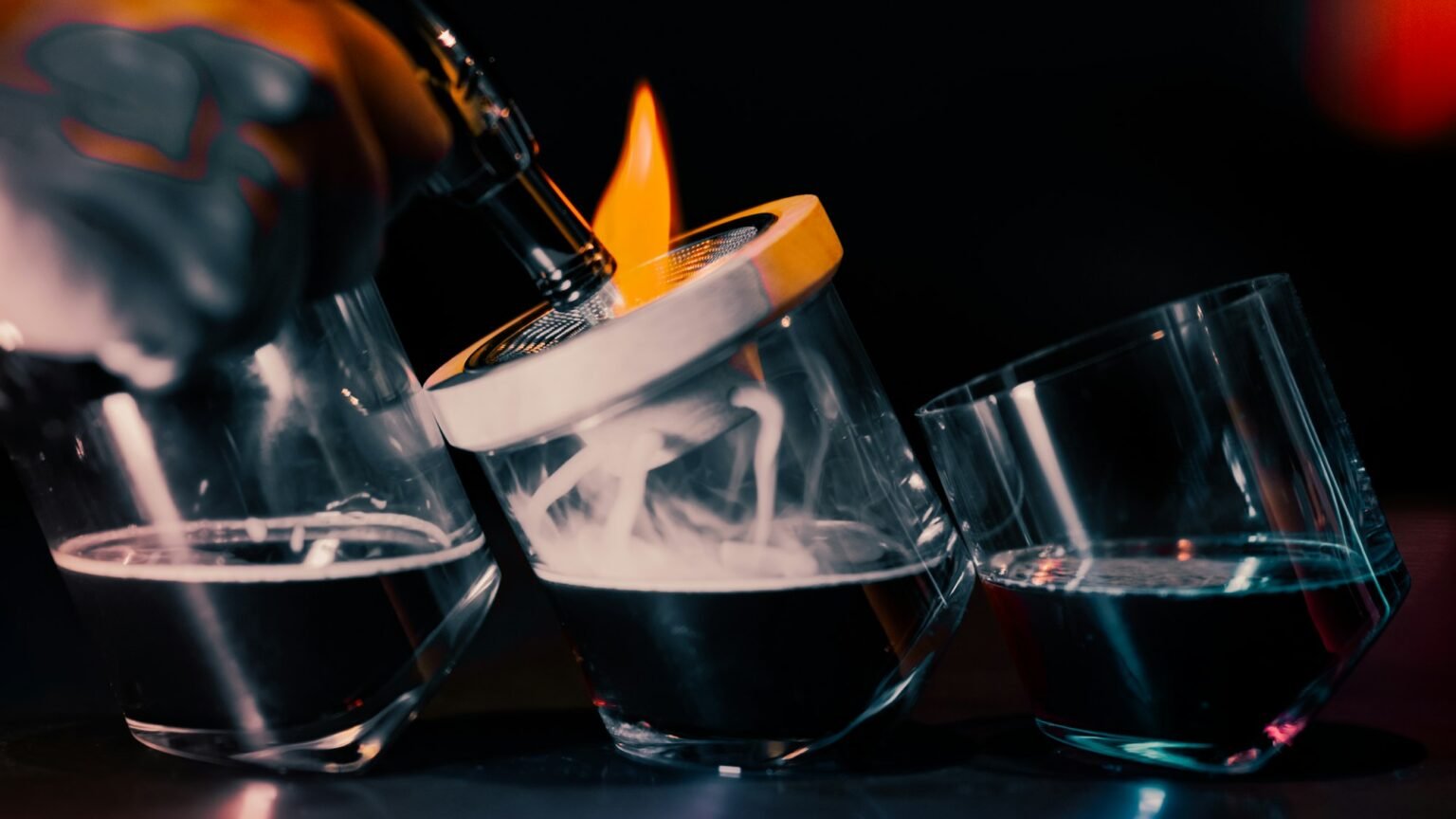 A flamed orange peel over a row of cocktails