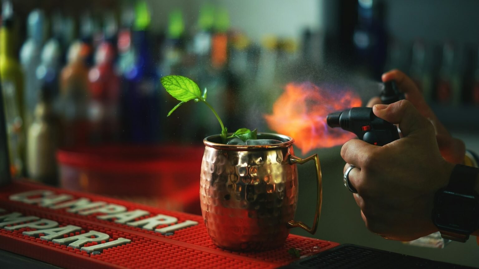 A bartender torching the garnish on a copper mug