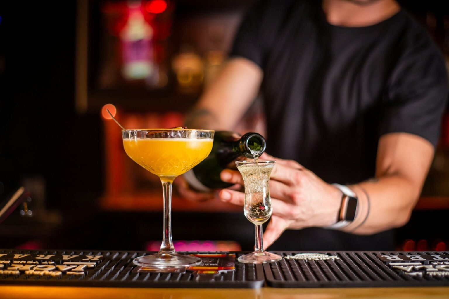 A bartender pouring a golden cocktail